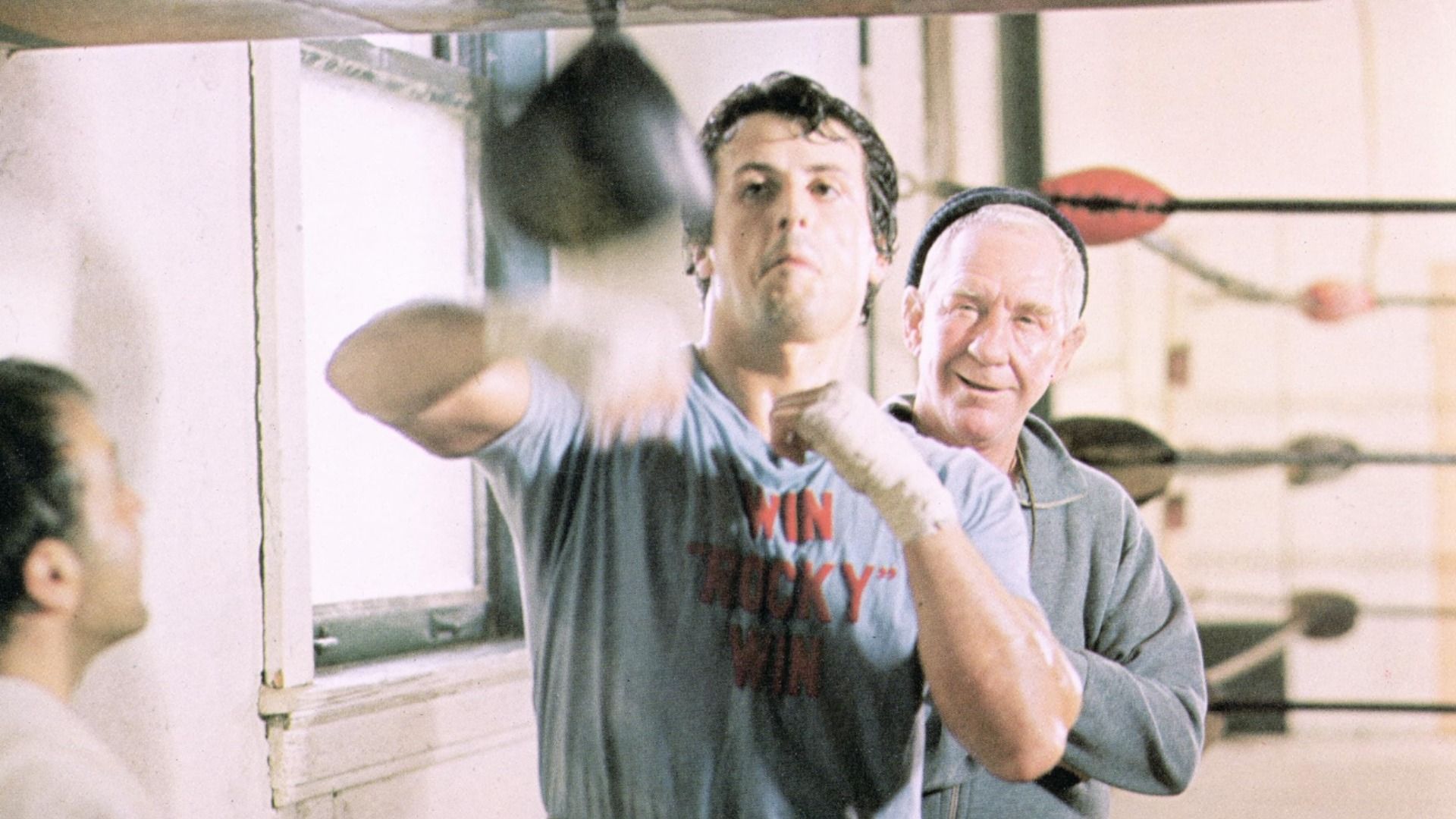 Actorul Sylvester Stallone lovește un sac de box mic într-o sală de box