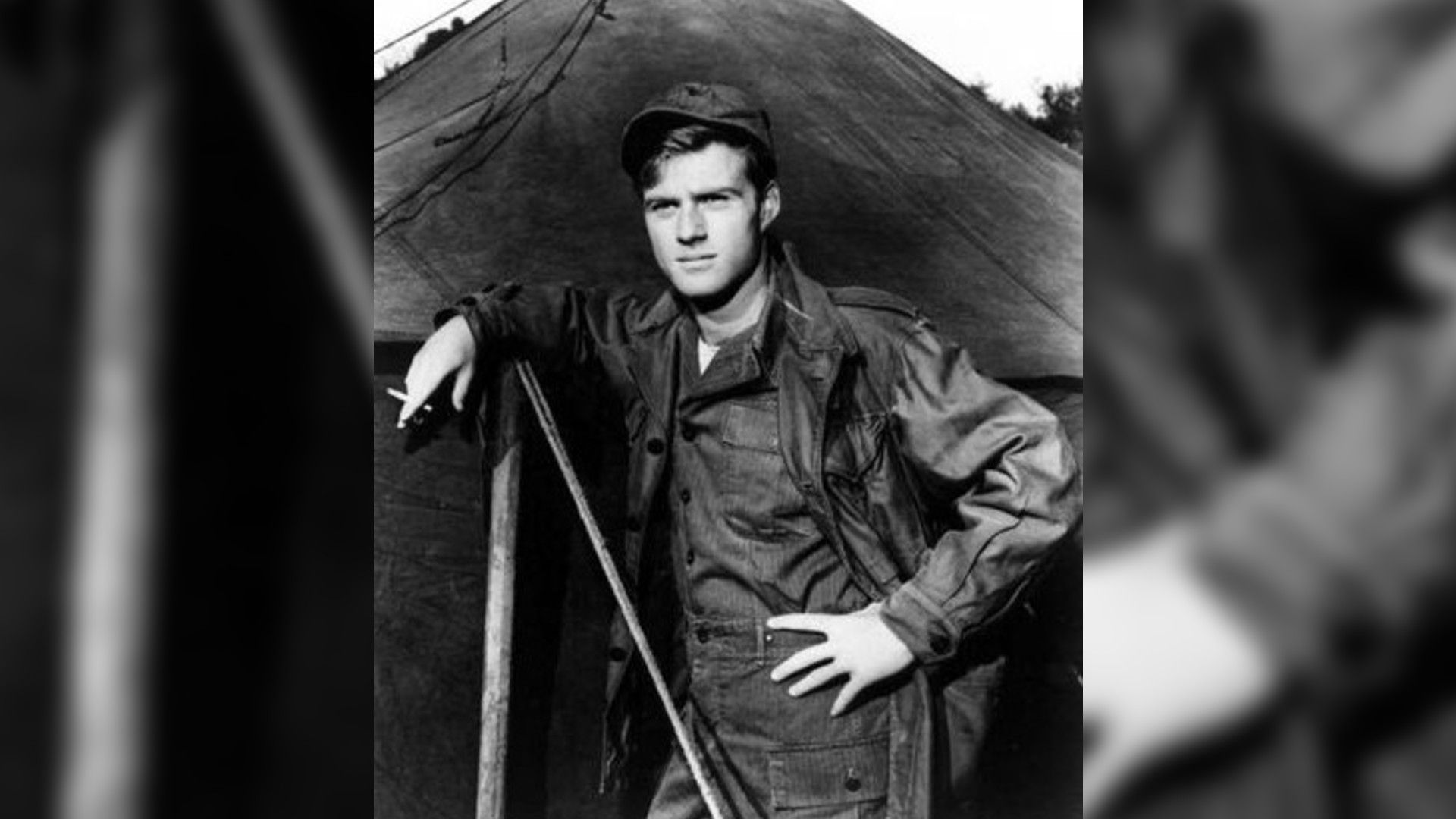 Fotografie în alb-negru cu tânărul Robert Redford în uniformă militară stând lângă un cort, scenă din filmul "War Hunt"