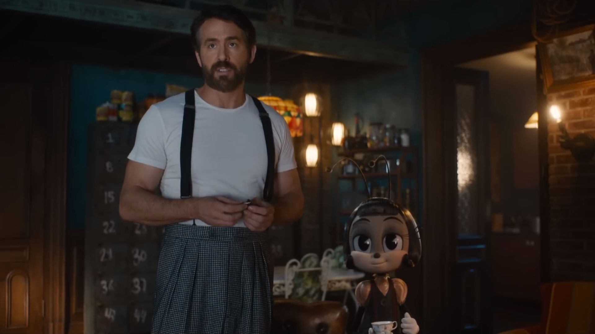 Ryan Reynolds într-un tricou alb cu bretele stă lângă un personaj furnicuță din desene animate care ține o ceașcă de ceai