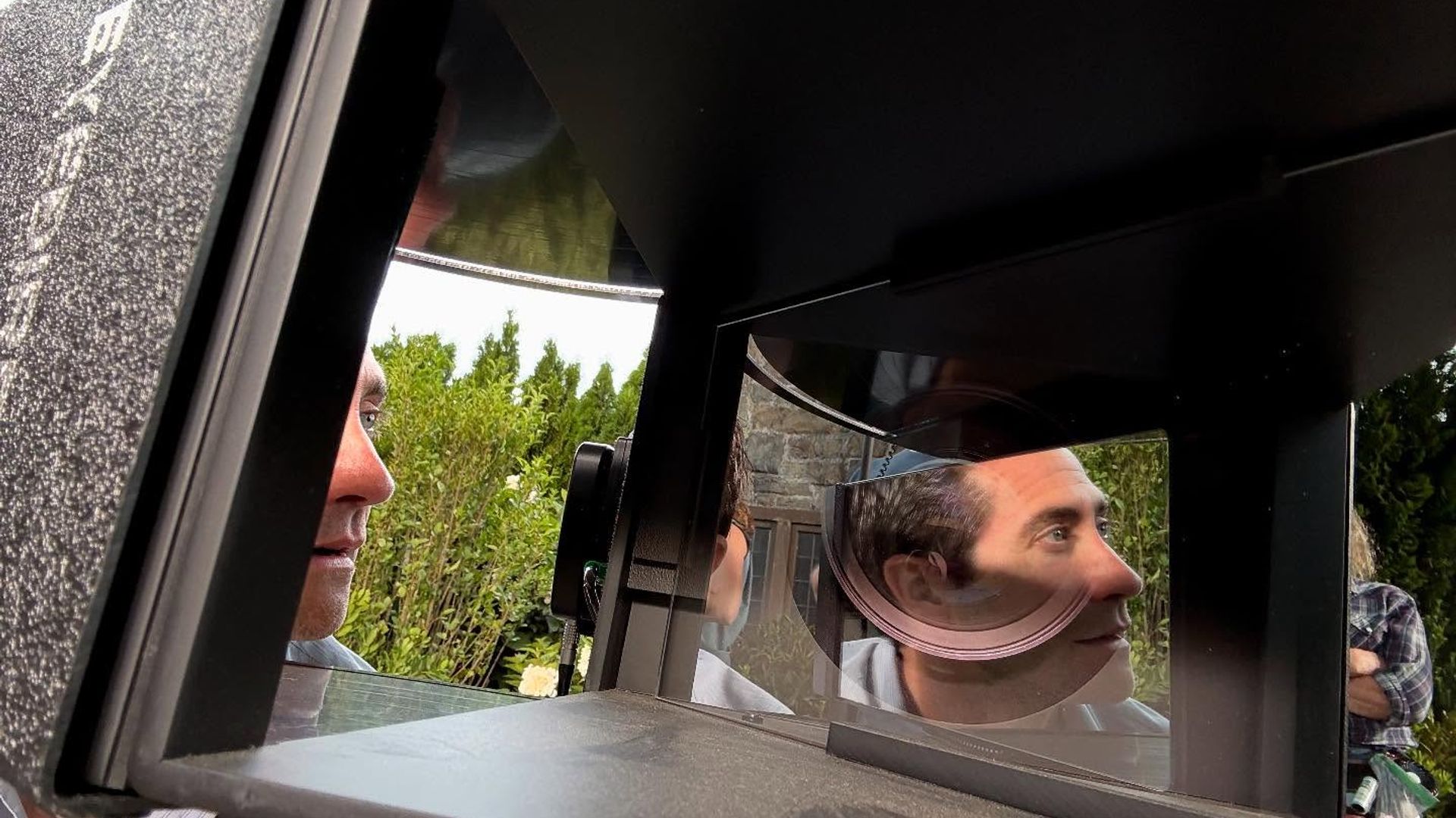 Jake Gyllenhaal se uită într-un echipament cu oglinzi și lentile, fața sa reflectându-se în suprafețele optice