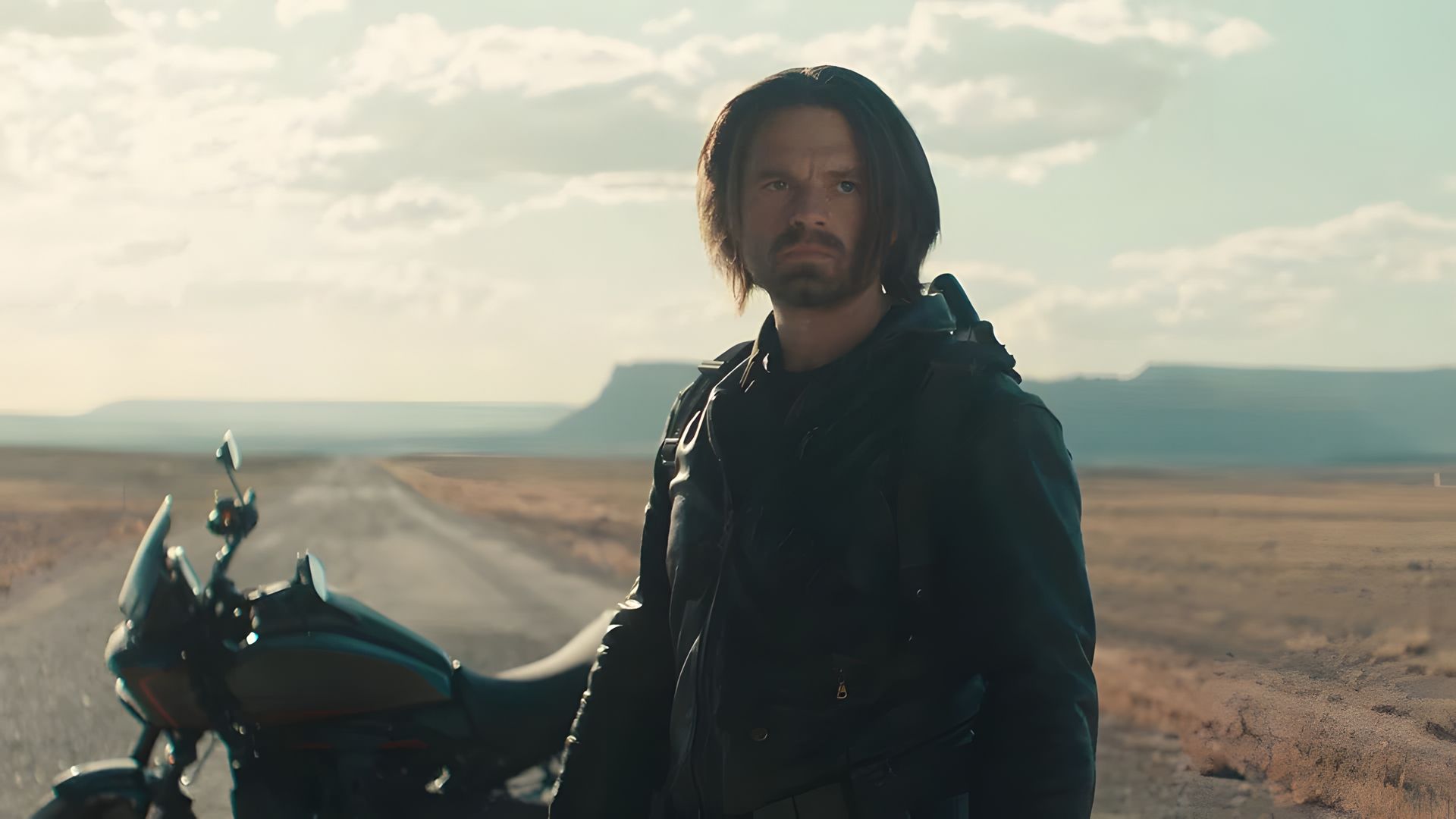 Sebastian Stan în rolul Winter Soldier-ului pe fundalul unei motociclete și al unui drum