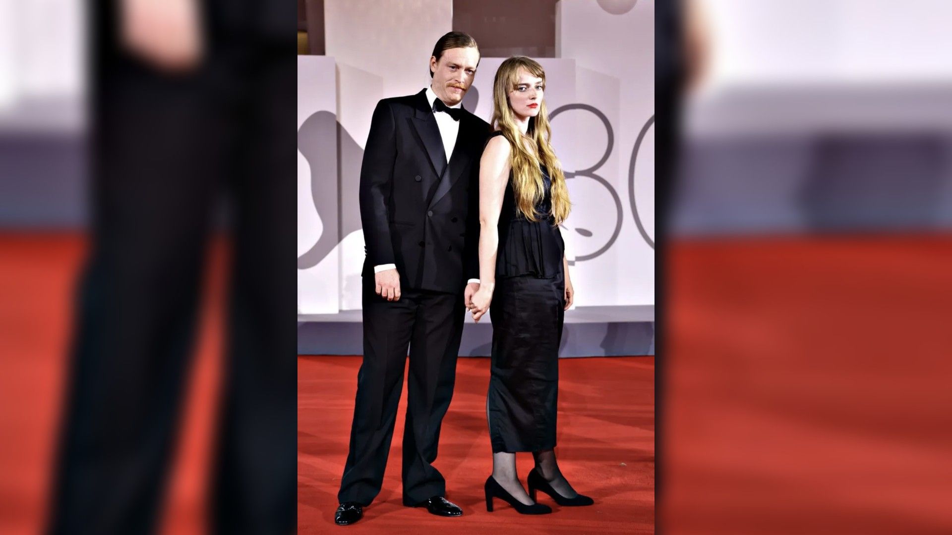 Caleb Landry Jones și Katya Zvereva în ținute de seară pozează pe covorul roșu, ținându-se de mână