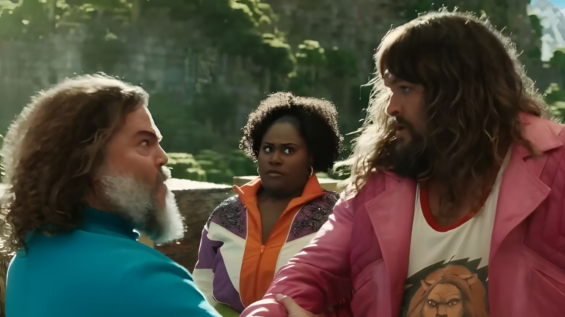 Jack Black într-un tricou albastru și Jason Momoa într-o jachetă roz dându-și mâinile cu vigoare